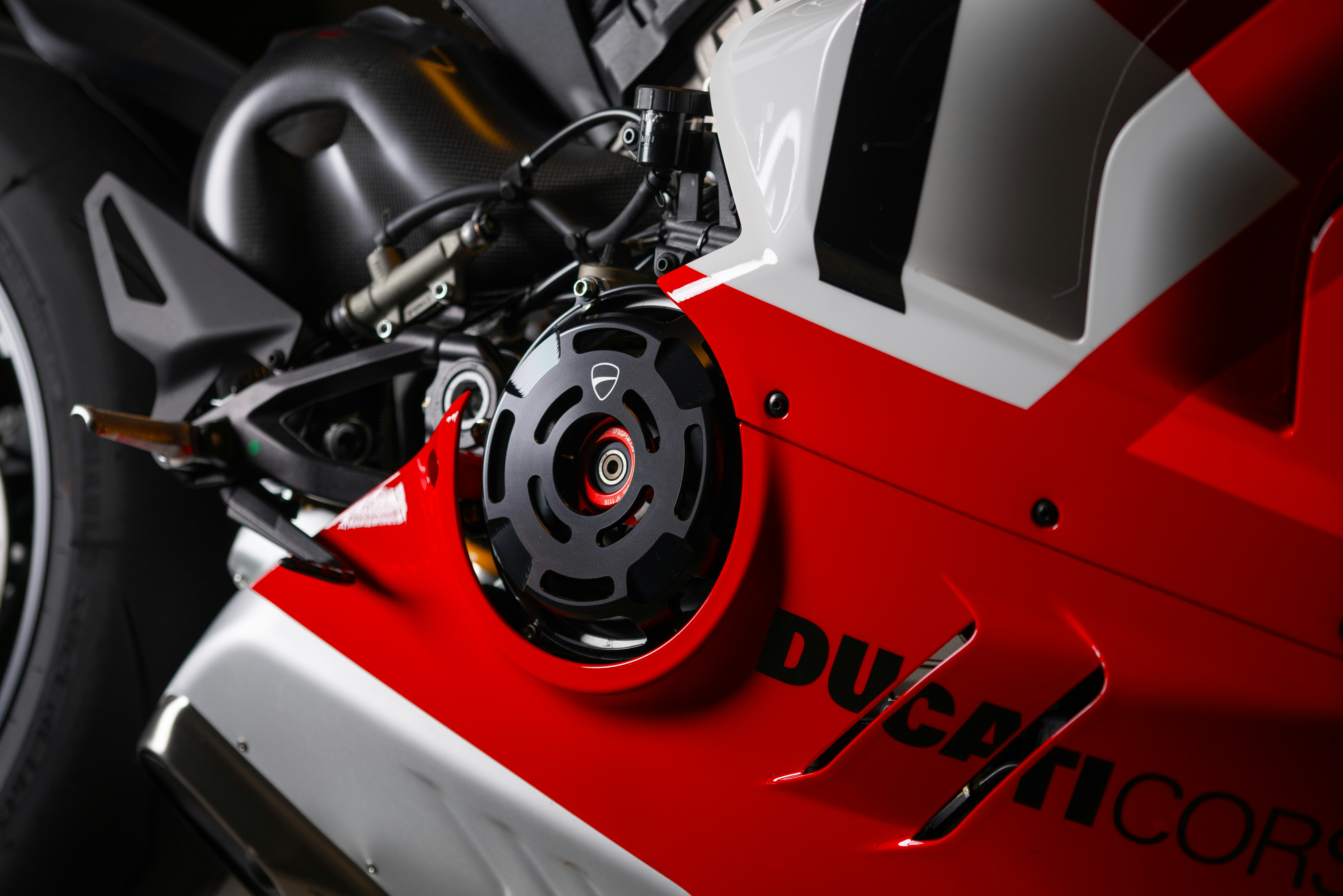 AI-Generated Image: First-person perspective from inside a futuristic racing cockpit. The steering wheel and dashboard are in sharp focus, showing digital readouts and intricate controls. The blurred windscreen ahead reveals a dynamic track with abstract light streaks, rain droplets enhancing the motion. Intense, high-speed experience, conveying adrenaline. Dominant dark tones with vibrant UI highlights in #00A6FB and #FF2A00.